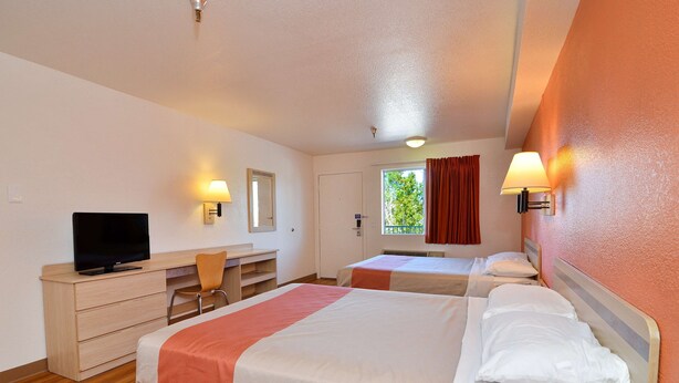 A hotel room with two beds, a desk with a television, and a window with curtains. - Motel 6 Twentynine Palms, CA (Twentynine Palms)