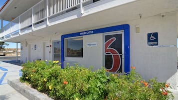 Un motel con un letrero que dice 'Welcome', un letrero de 'Elevator', un letrero con el número '6' y un letrero de 'Reserved' que indica un espacio de estacionamiento para discapacitados.
