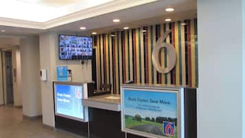 A reception area with a large number '6' sign, a television mounted on the wall, and two digital screens displaying promotional content.