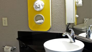 A bathroom with a yellow soap dispenser, a white sink, and a mirror.
