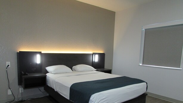 A hotel room with a bed, nightstands, and a wall-mounted TV. - Motel 6 West Des Moines, IA (West Des Moines)