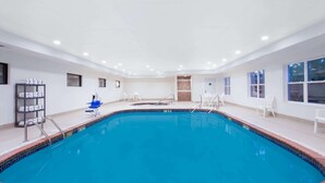 Ein Hallenbad mit klarem Wasser, umgeben von weißen Wänden und einem gefliesten Boden.