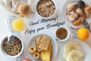 A breakfast table with various food items including cereal, pastries, and fruit.