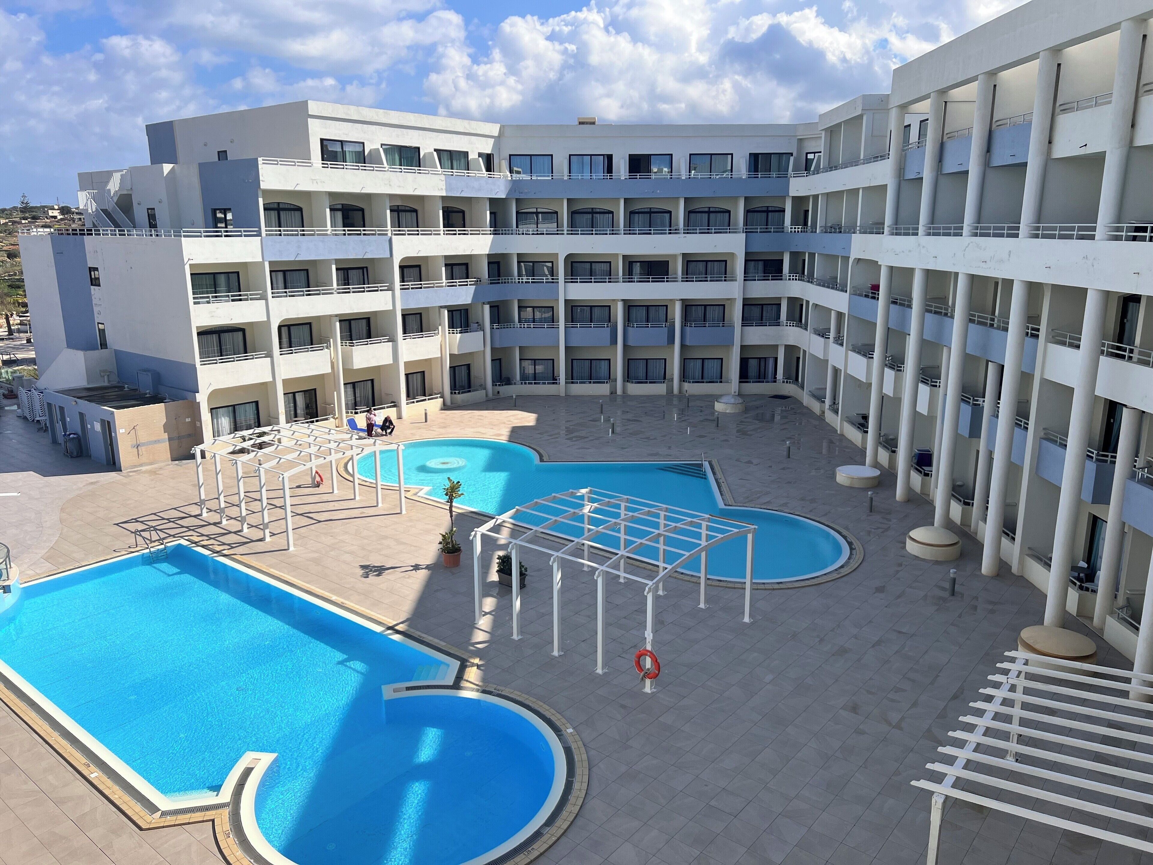 Un hôtel à étages, doté d’une cour intérieure avec une piscine et d’espaces extérieurs aménagés pour se détendre.