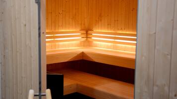 Een sauna met houten banken en inbouwbanken, een ladder en een deur.