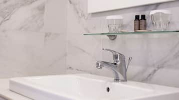 A bathroom with a white sink, a mirror, and a glass shelf with toiletries.
