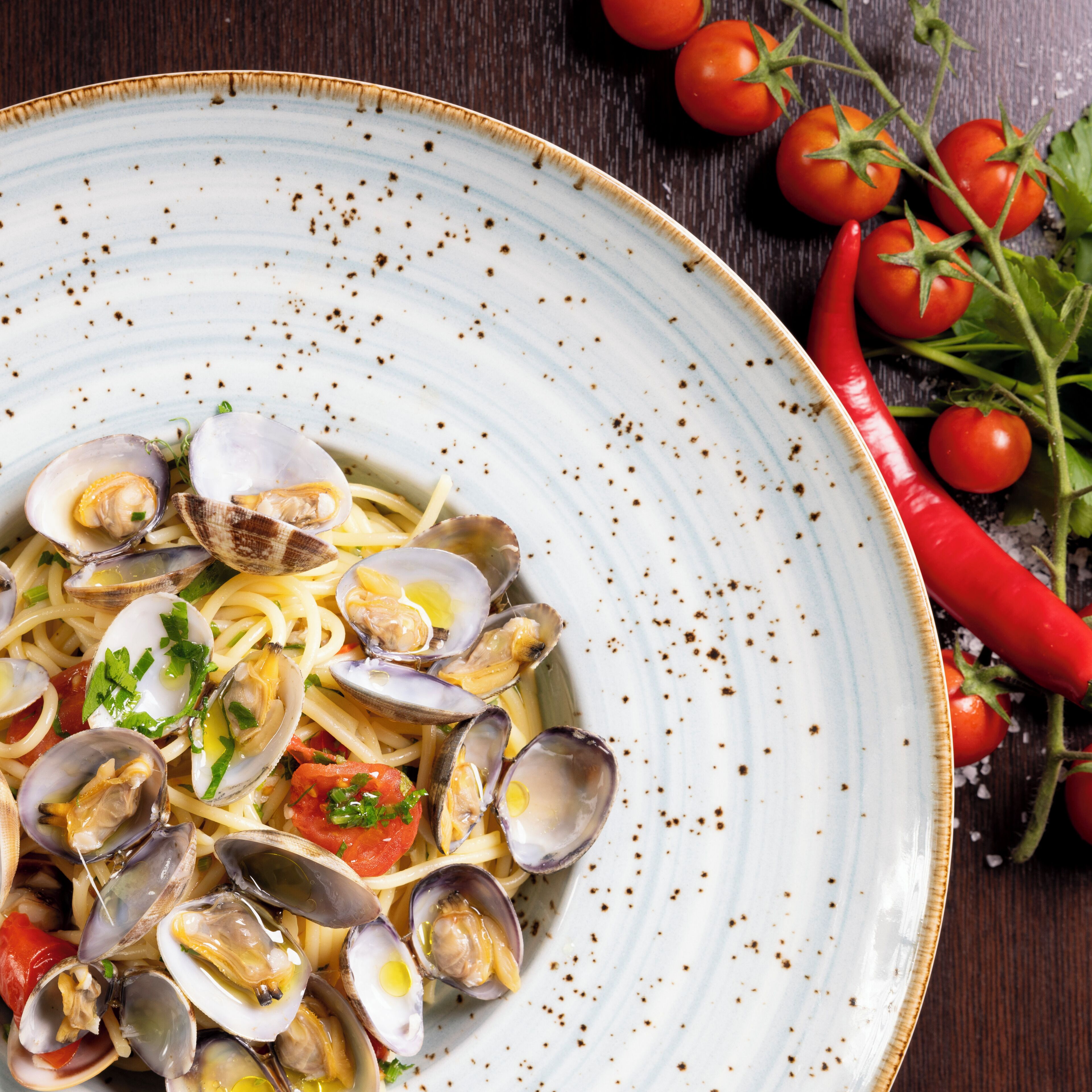 Un plato de pasta con almejas y tomates cherry.