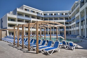 A poolside area with lounge chairs and a wooden pergola.