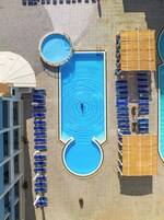 An aerial view of a swimming pool area with multiple pools and sun loungers arranged around it.