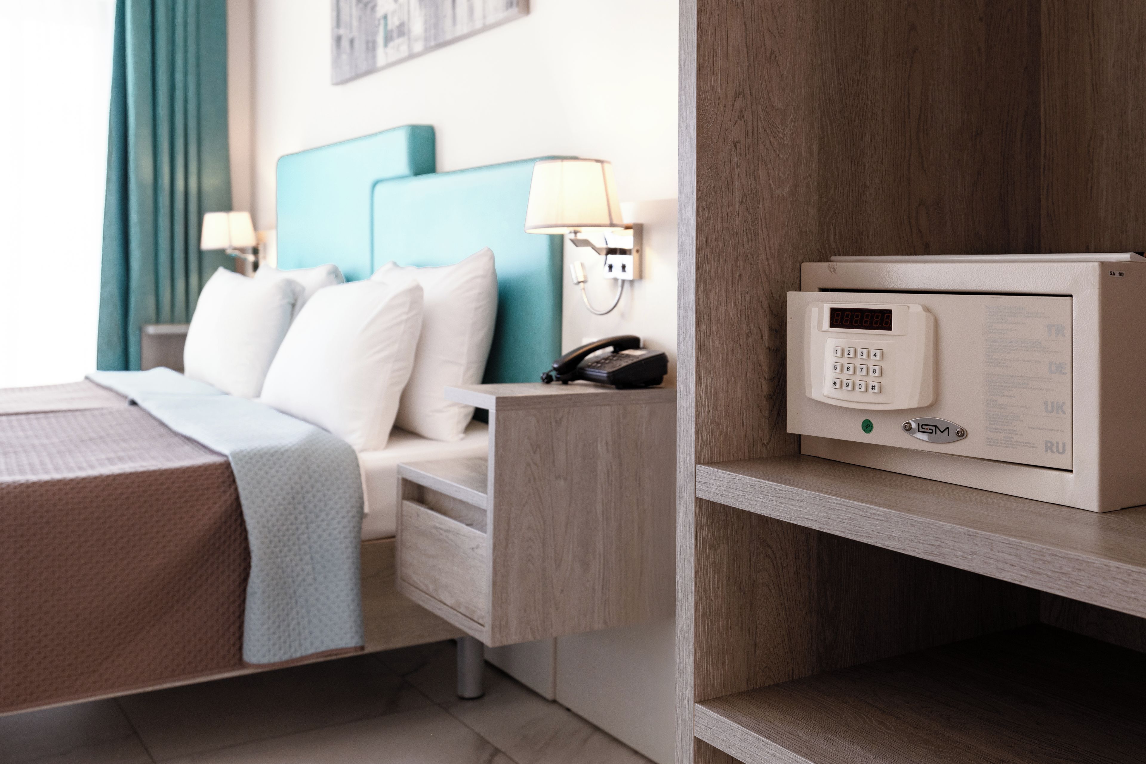Ein Hotelzimmer mit einem Bett, einem Schreibtisch, einem Telefon und einem digitalen Safe.