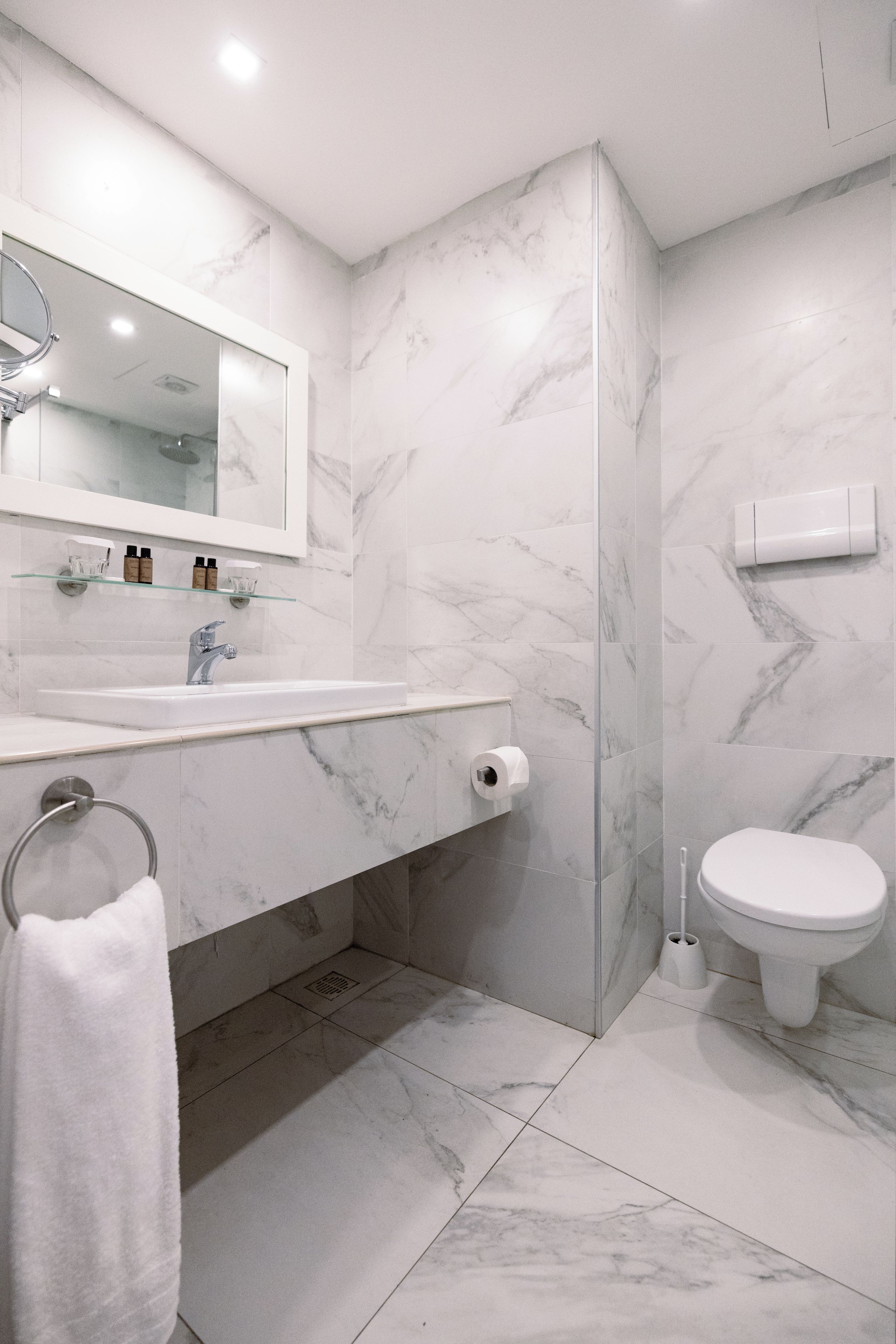 Un baño moderno con lavamanos de mármol, inodoro y zona de ducha.