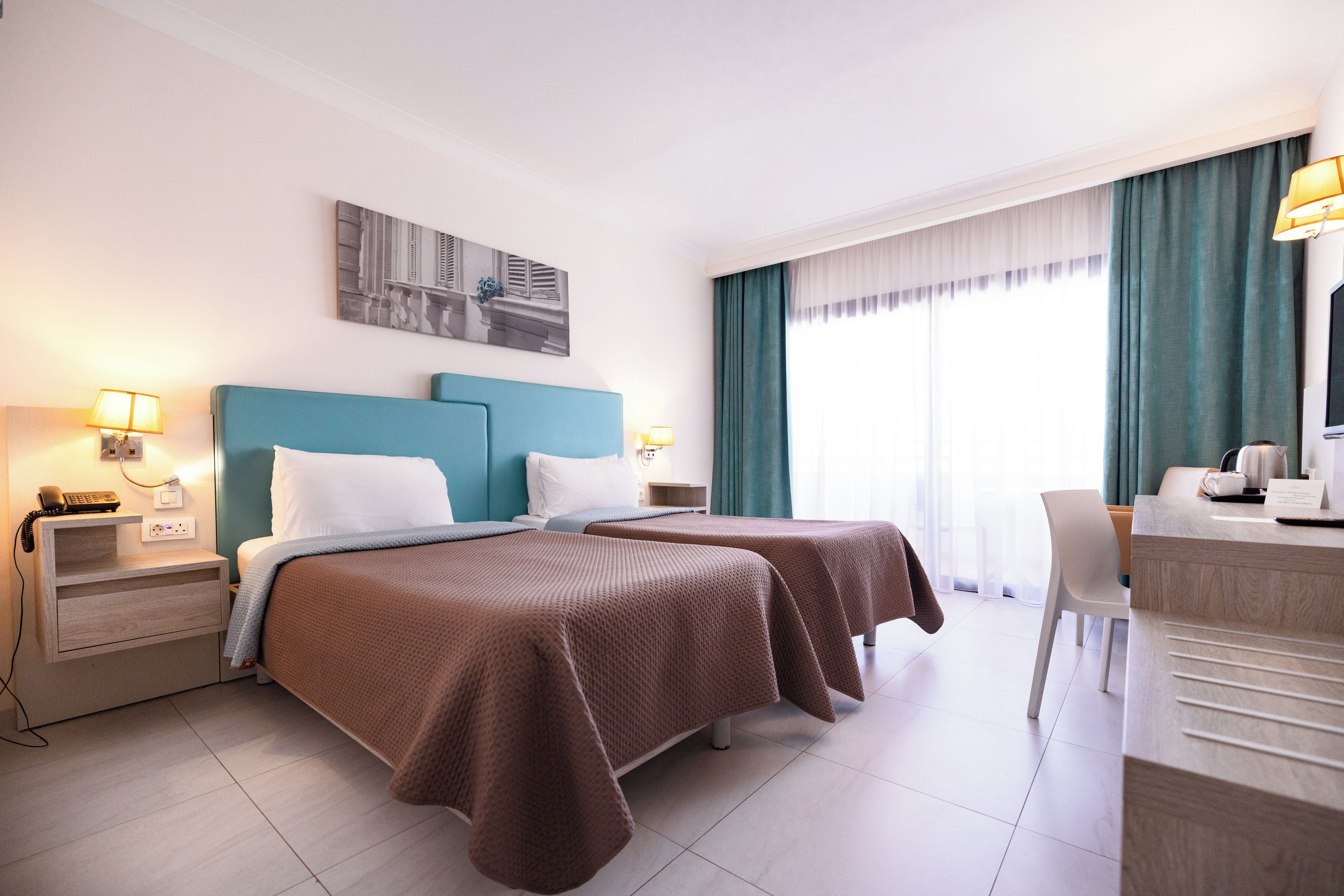 A hotel room with two beds, a desk, and a chair.