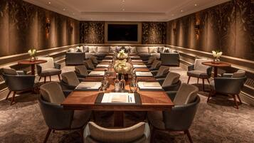 A conference room with a long table, multiple chairs, and a large screen.