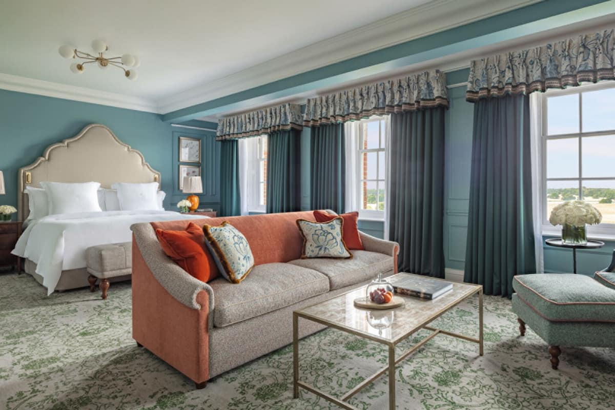 A hotel room with a large bed, a sofa, a chair, and a coffee table.