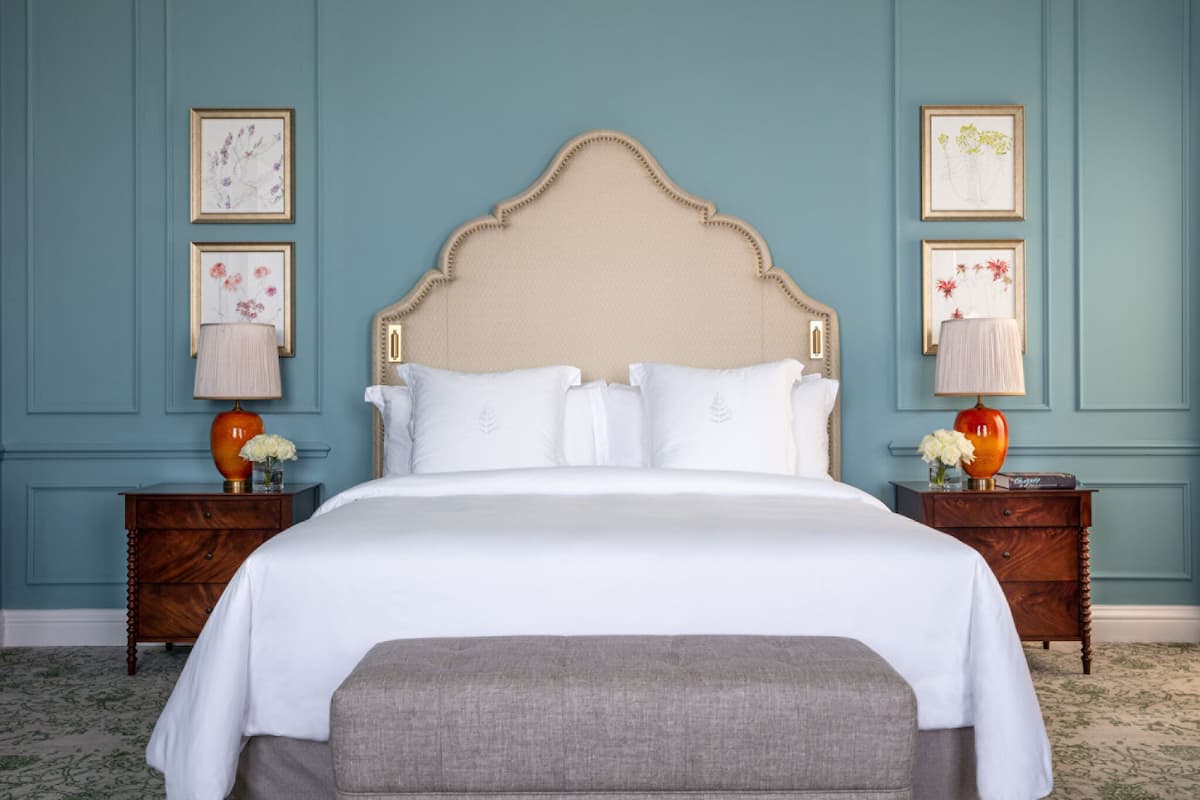 A neatly made bed with a wooden headboard, flanked by two nightstands with lamps and vases.