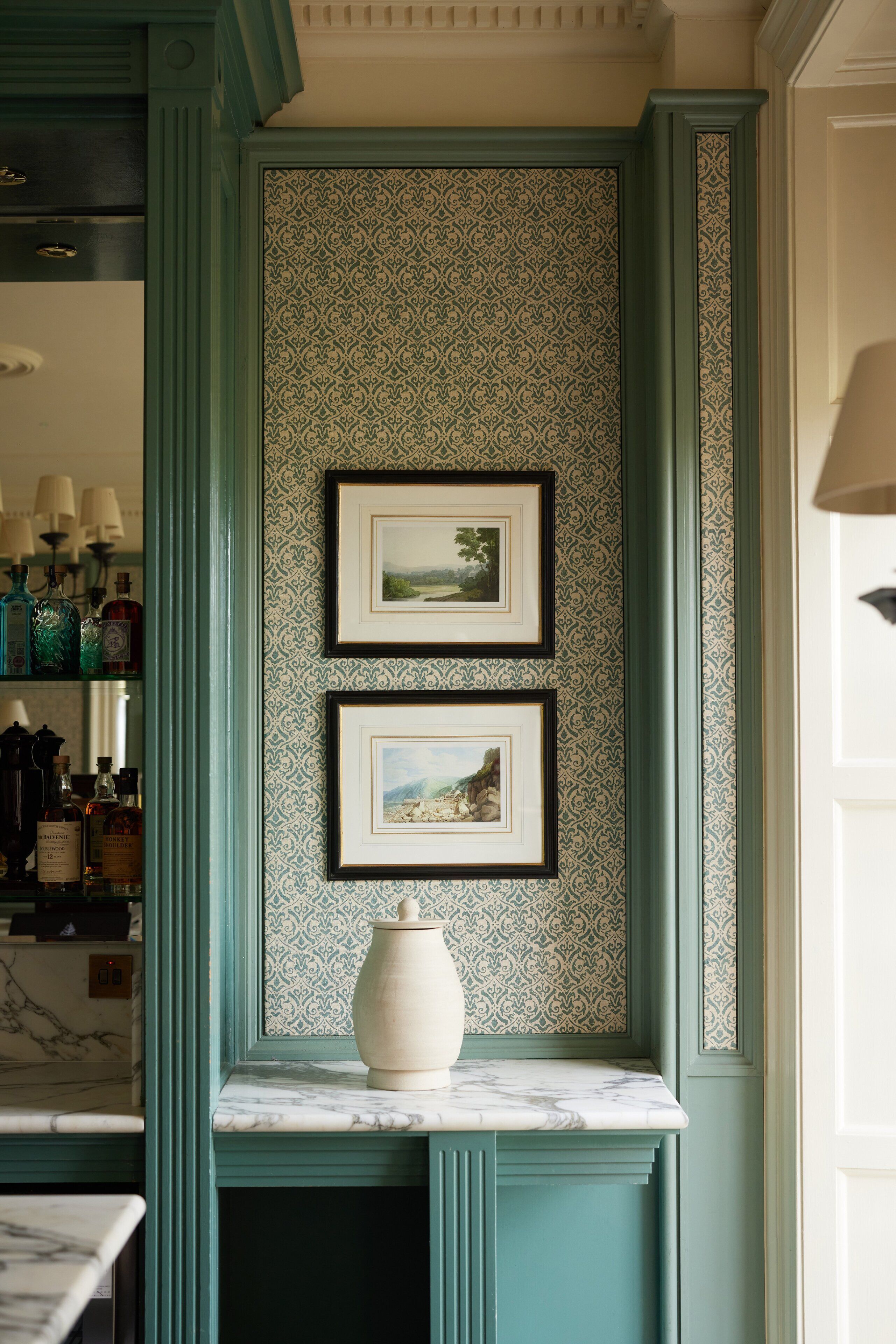 A kitchen with a marble countertop, a decorative vase, and two framed pictures on the wall.