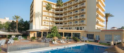 Alberca al aire libre, sombrillas en la alberca y camastros