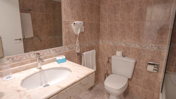 A bathroom with a sink, mirror, toilet, and a hairdryer mounted on the wall. - BLUESEA Costa Serena (Torremolinos)