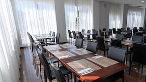 A conference room with multiple tables and chairs, large windows with sheer curtains, and a tiled floor. - BLUESEA Costa Serena (Torremolinos)
