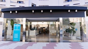 A hotel entrance with glass doors, a blue signboard, and a potted plant. - BLUESEA Costa Serena (Torremolinos)