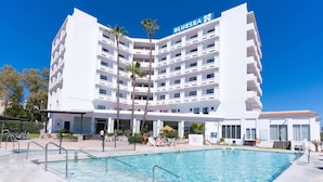 A multi-story hotel with a pool area, palm trees, and a clear blue sky. - BLUESEA Costa Serena (Torremolinos)