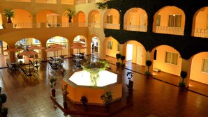 A spacious courtyard with multiple seating areas, a central fountain, and potted plants. - Hotel Misión Orizaba (Orizaba)