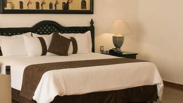 A hotel room with a large bed, two bedside tables with lamps, a chair, and a small table.