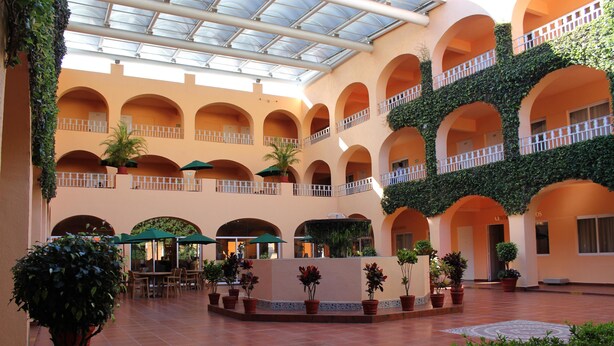 A spacious atrium with multiple balconies, potted plants, and a central seating area. - Hotel Misión Orizaba (Orizaba)