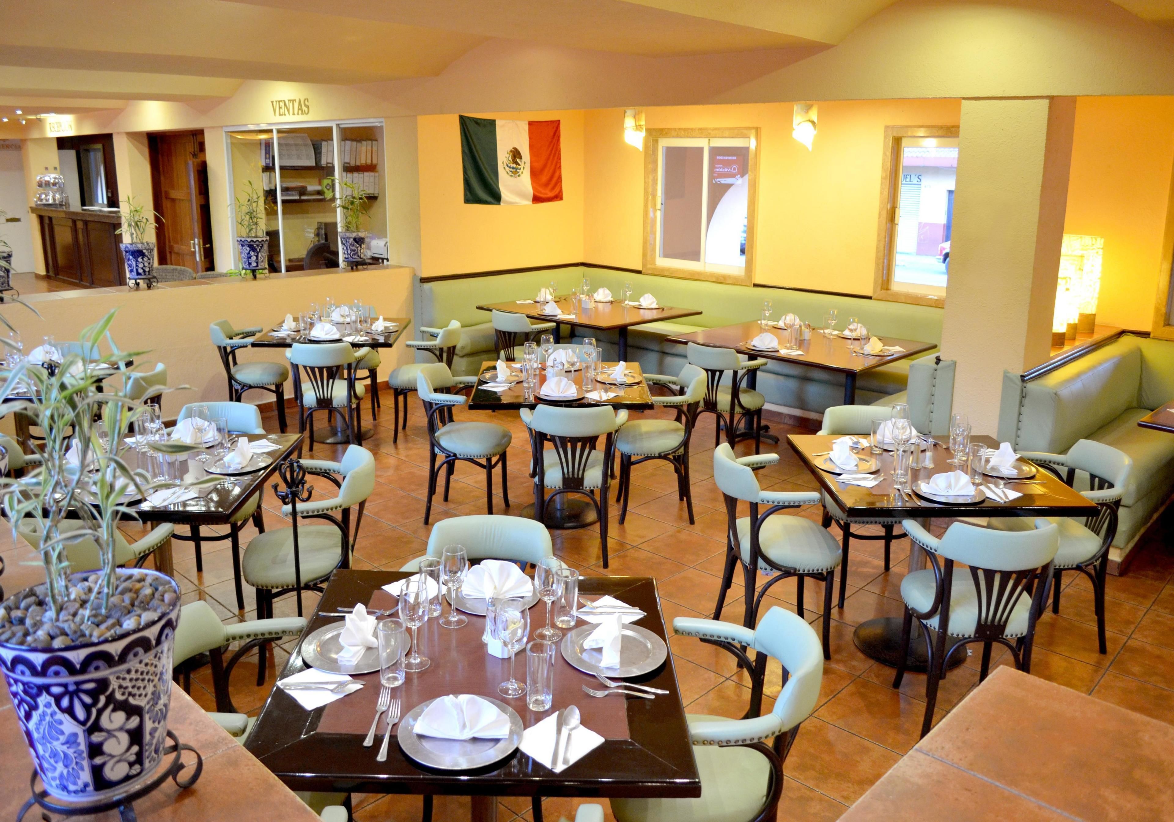 A restaurant with multiple dining tables and chairs, a flag on the wall, and a counter area.