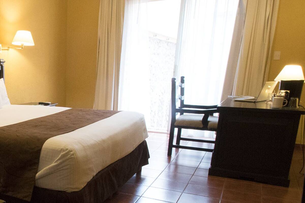 Ein Hotelzimmer mit Bett, Nachttischen, Schreibtisch und Stuhl.