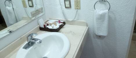 Un baño con lavamanos, espejo y toallero.