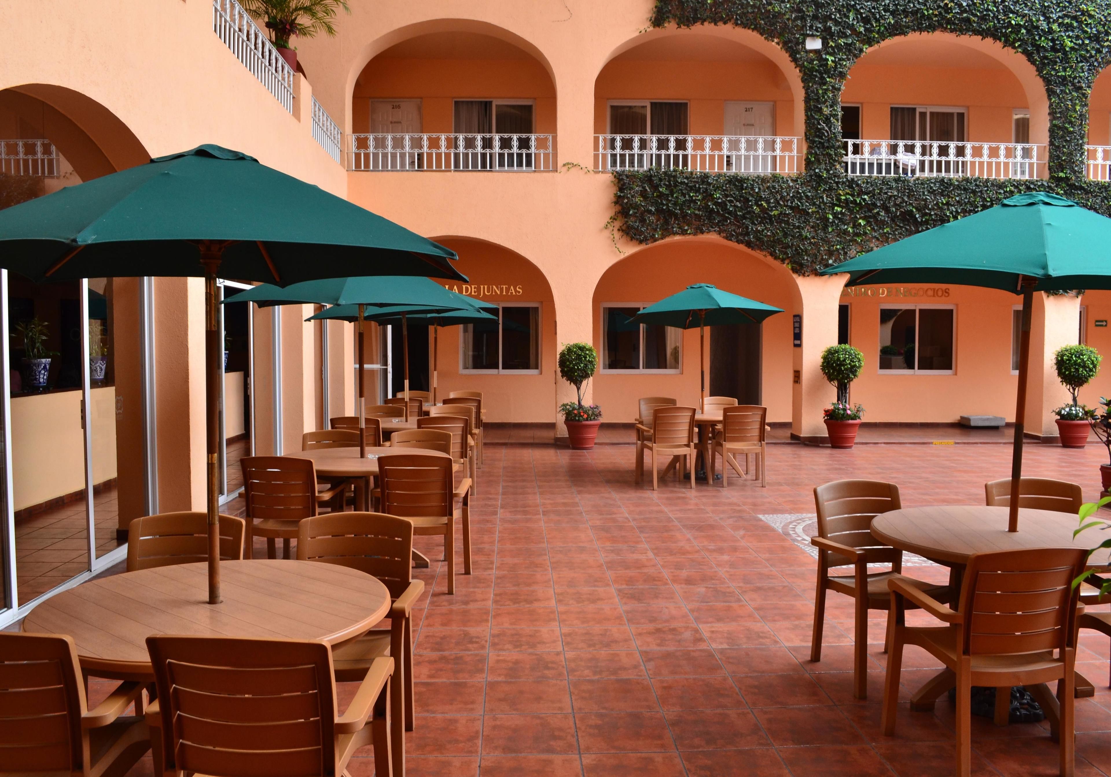 A courtyard with outdoor seating, potted plants, and a tiled floor.