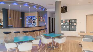 A modern bar area with a counter, bar stools, and a wall-mounted display of liquor bottles.