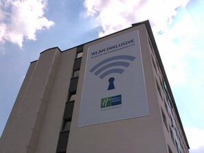 A building with a sign advertising WiFi and a Holiday Inn Express logo. - Holiday Inn Express München-Messe by IHG (Feldkirchen)