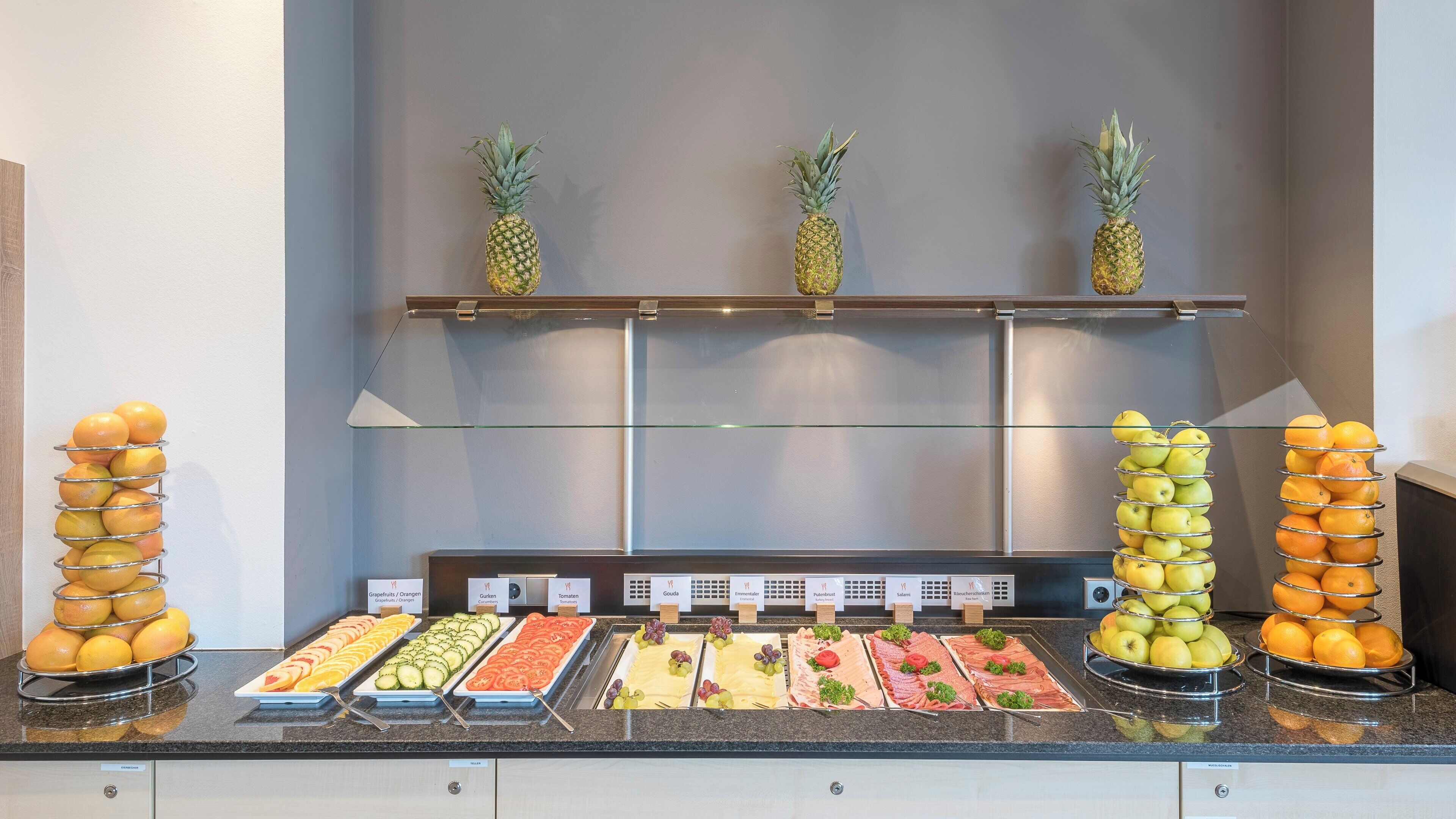 Un bufé con diversas opciones de comida y frutas exhibidas en estantes.