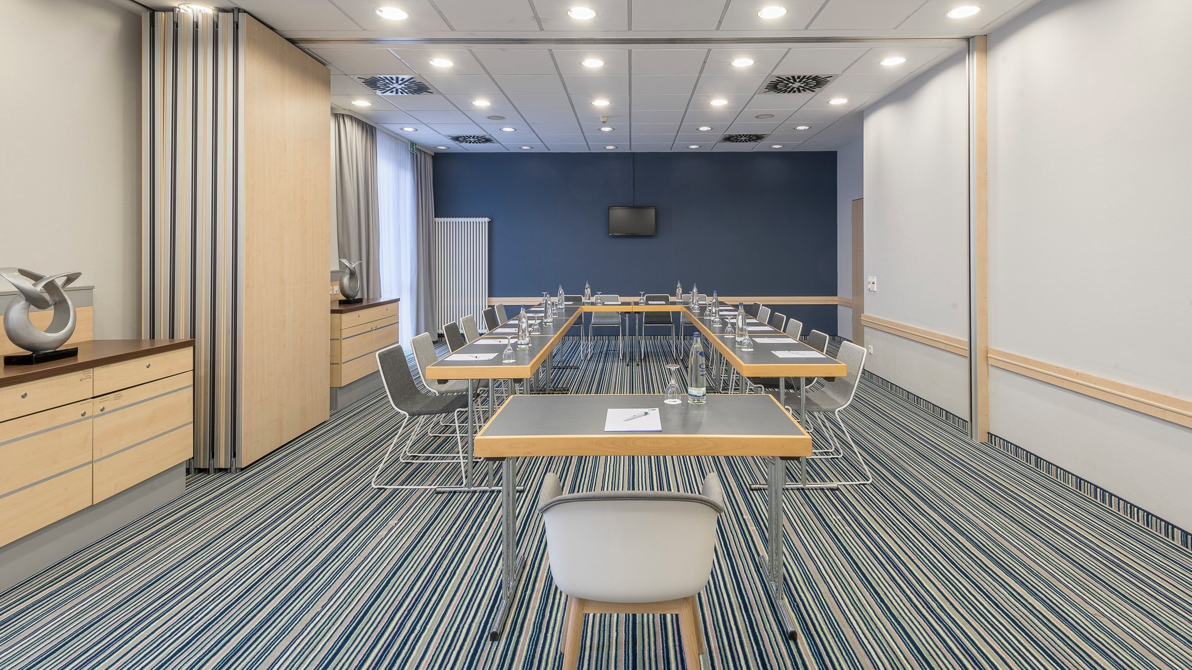 A conference room with a long table, chairs, and a whiteboard.