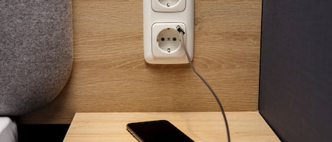 Un teléfono inteligente conectado a un enchufe sobre una superficie de madera.