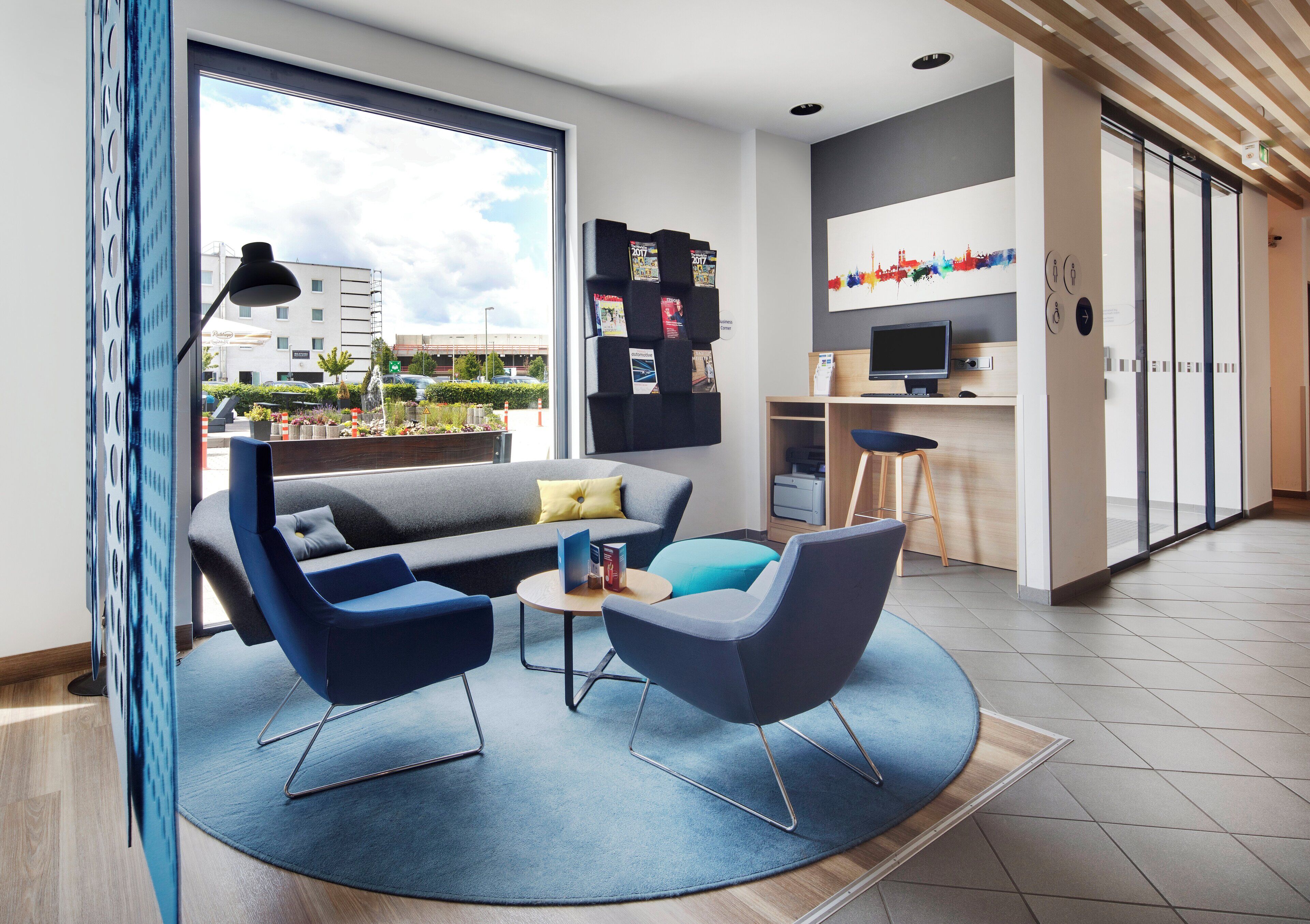 A modern living room with a sofa, two armchairs, a coffee table, and a bookshelf with magazines.
