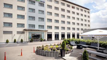 A hotel with a modern facade, a central entrance, and a patio area with seating and planters.