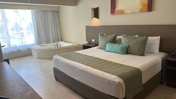 Ein Hotelzimmer mit einem großen Bett, einer Sitzecke, einer Badewanne und Blick ins Freie.