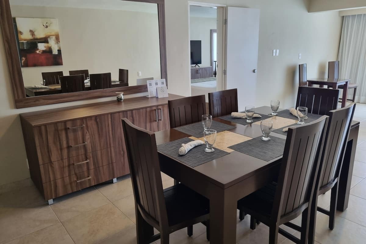 A dining area with a wooden table, chairs, a large mirror, and a cabinet.
