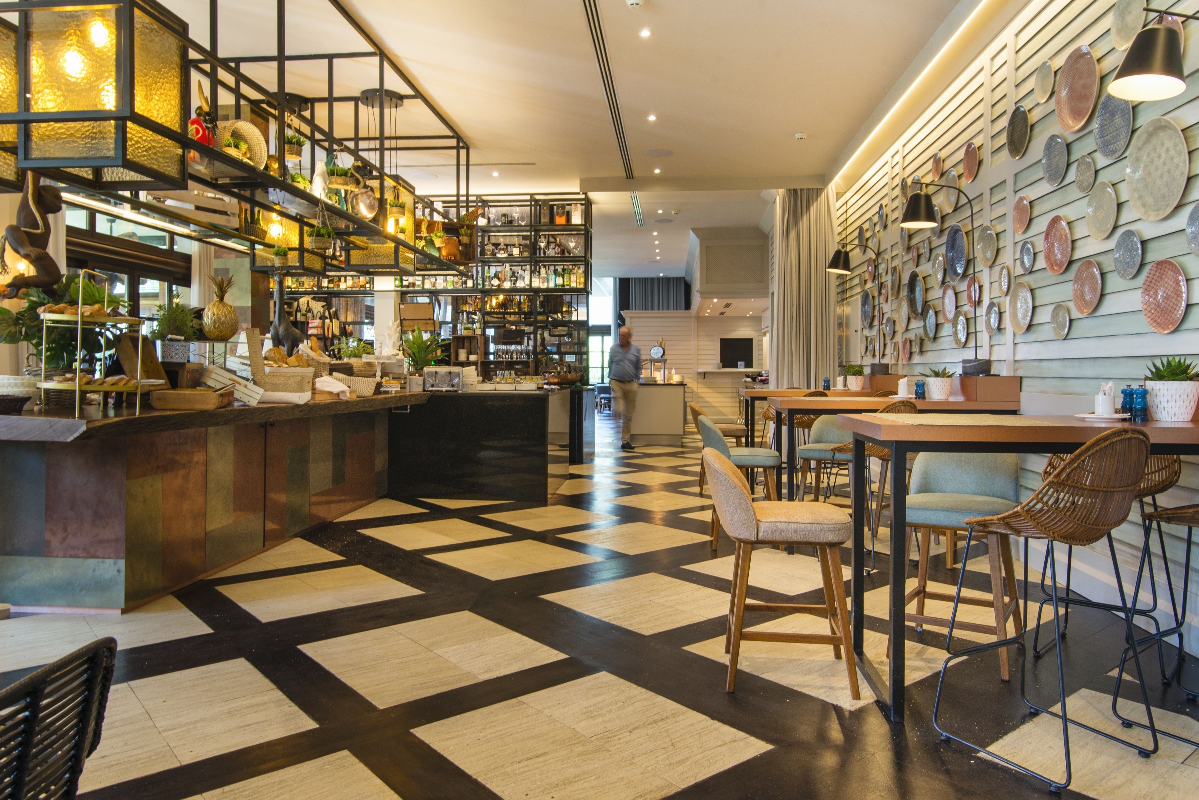 A modern bar area with a checkered floor, wooden furniture, and a variety of decorative items on shelves.
