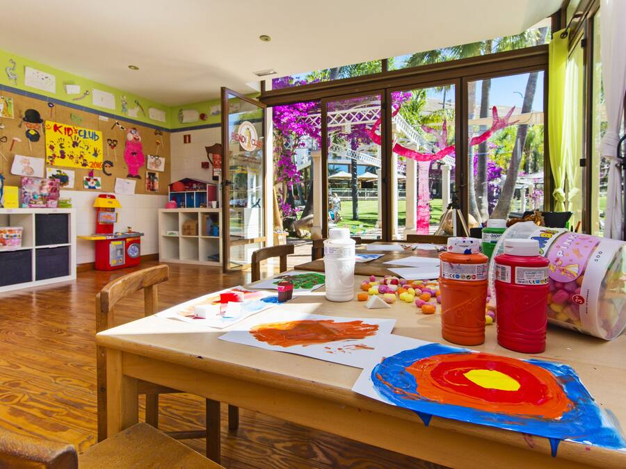 Ein Klassenzimmer mit Kunstmaterialien, einem Bulletinboard und Blick auf einen Garten.