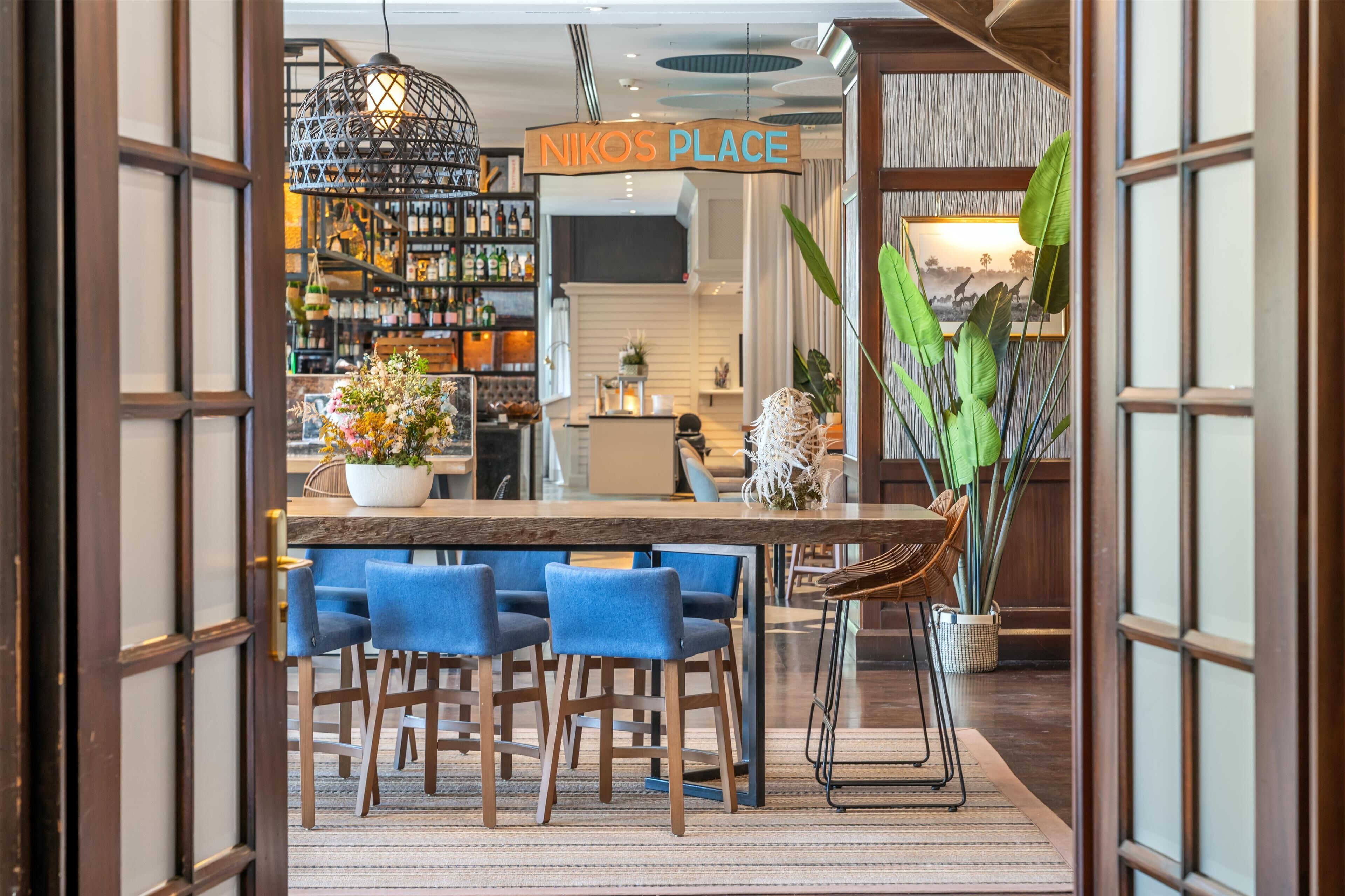 A restaurant with a wooden bar, blue chairs, and a hanging light fixture.