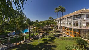 Un resort con piscina, palmeras y un edificio con balcón.