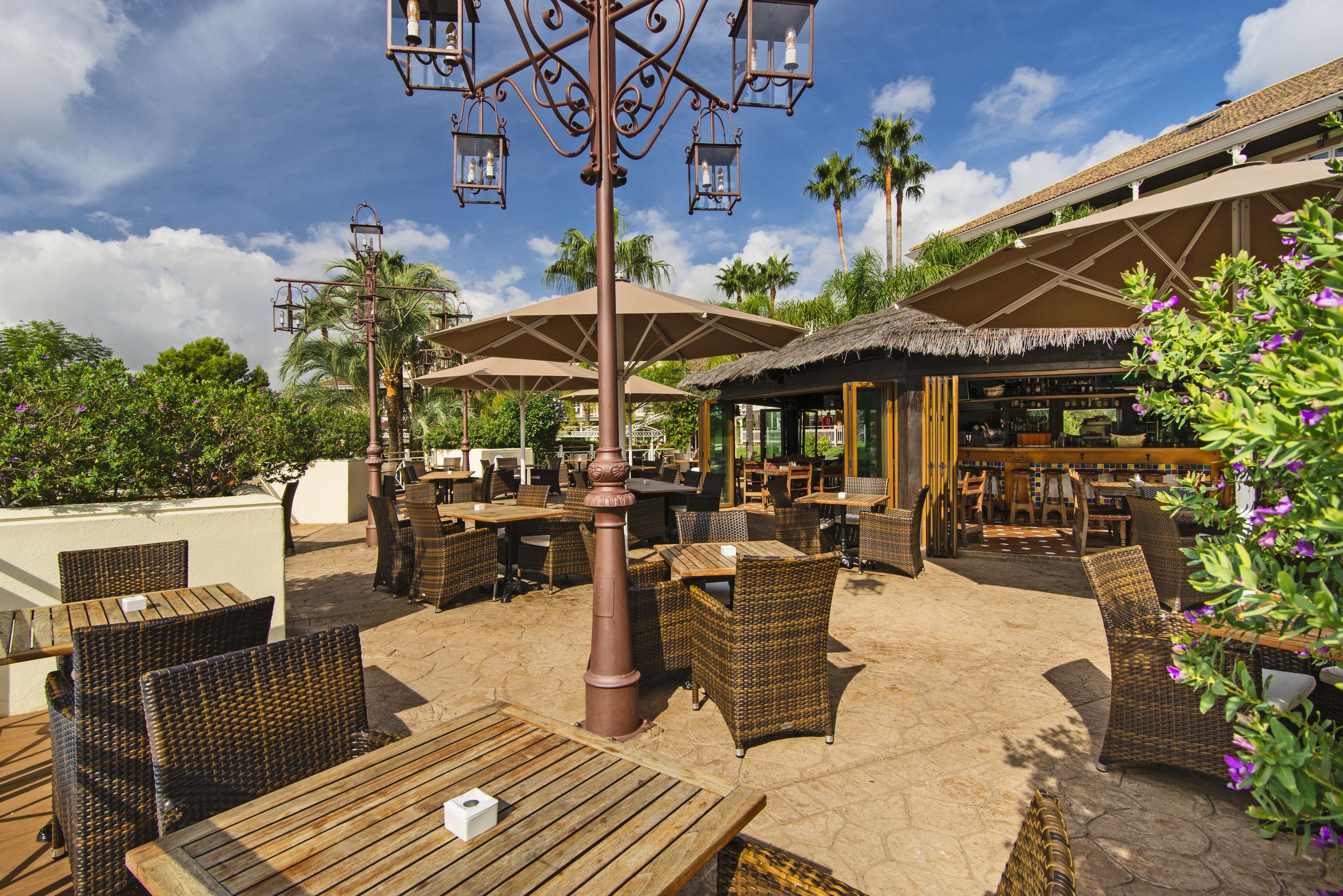 An outdoor patio area with wicker furniture, umbrellas, and a bar.