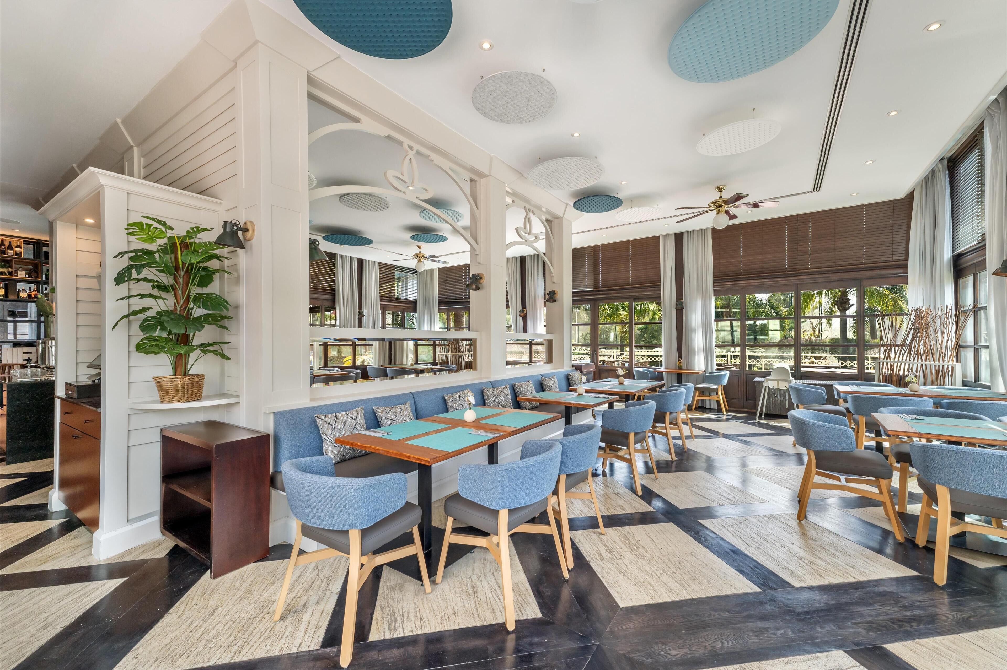 A modern restaurant with high ceilings, large windows, and a mix of seating arrangements including booths and tables.
