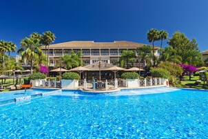 Una piscina techada, una piscina al aire libre, sombrillas