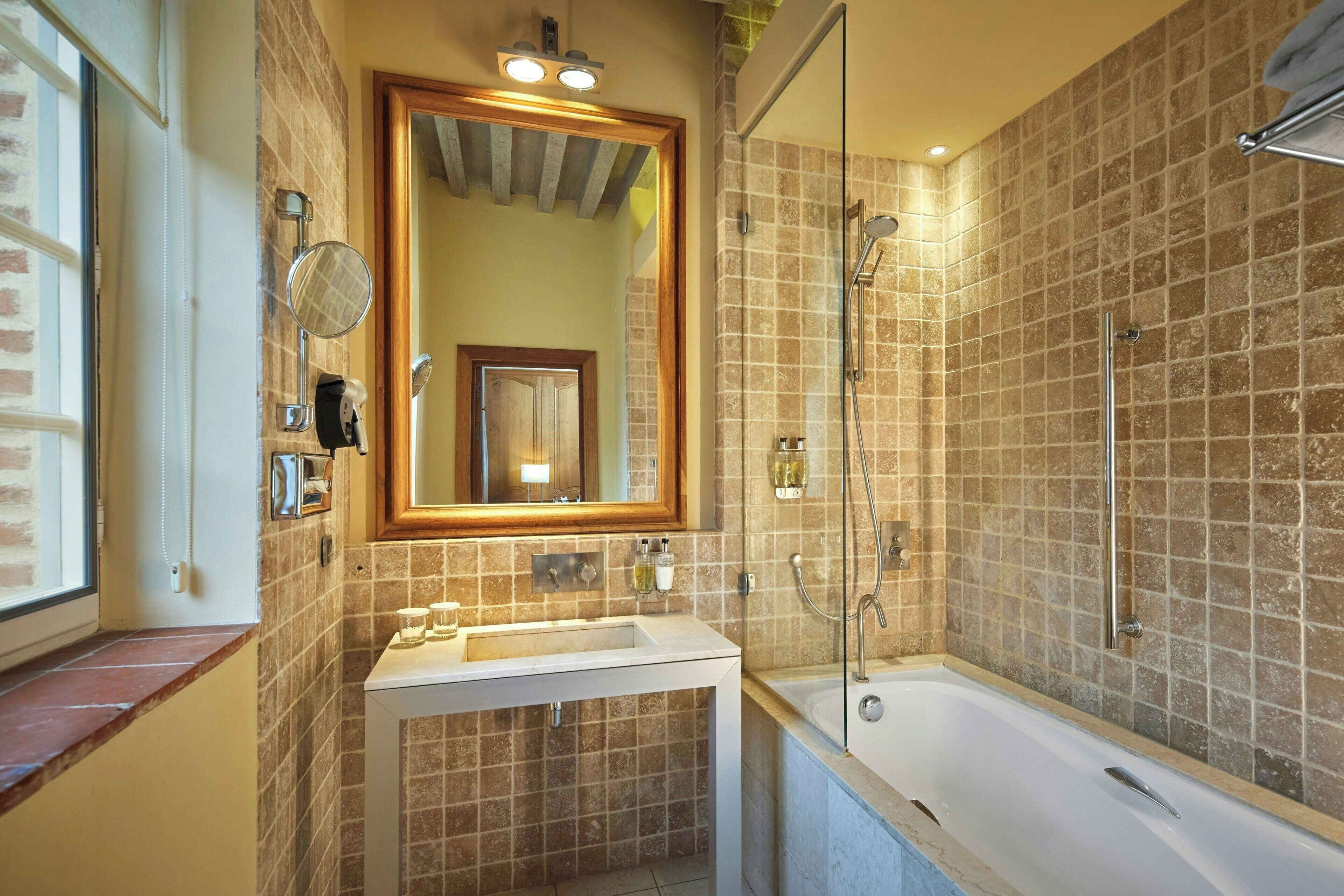Een badkamer met een bad, een wastafel, een spiegel en een douche.