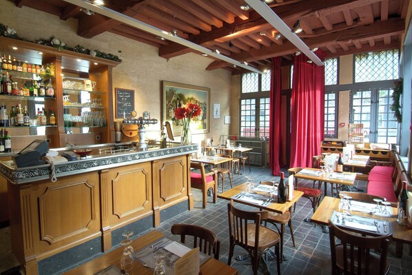 A restaurant with wooden furniture, a bar area, and large windows.